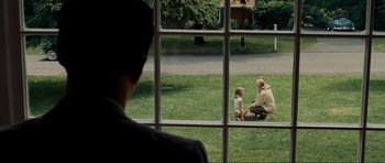 Movie still from “Revolutionary Road” (2008), directed by Sam Mendes – A man and a woman looking out a window at a child; Wide shot, Over the shoulder angle