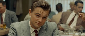 Movie still from “Revolutionary Road” (2008), directed by Sam Mendes – A man in a suit and tie sitting down; Close Up shot, Over the shoulder angle