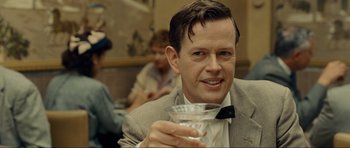 Movie still from “Revolutionary Road” (2008), directed by Sam Mendes – A man in a suit holding a drink in his hand; Close Up shot, Over the shoulder angle