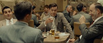 Movie still from “Revolutionary Road” (2008), directed by Sam Mendes – A man sitting at a table with a glass of beer; Medium shot, Over the shoulder angle