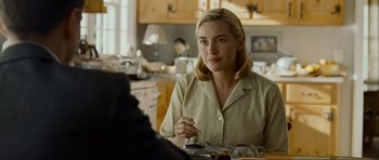 Movie still from “Revolutionary Road” (2008), directed by Sam Mendes – A woman sitting at a table in front of a man; Medium shot, Over the shoulder angle