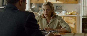 Movie still from “Revolutionary Road” (2008), directed by Sam Mendes – A woman sitting in front of a man at a table; Medium shot, Over the shoulder angle