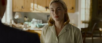 Movie still from “Revolutionary Road” (2008), directed by Sam Mendes – A woman with blonde hair is standing in a kitchen; Close Up shot, Over the shoulder angle
