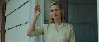 Movie still from “Revolutionary Road” (2008), directed by Sam Mendes – A woman in a beige shirt is waving; Medium shot, Low angle