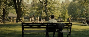 Movie still from “Revolutionary Road” (2008), directed by Sam Mendes – A man sitting on top of a bench in a park; Extreme Wide shot, Over the shoulder angle