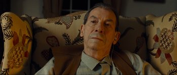 Movie still from “Revolutionary Road” (2008), directed by Sam Mendes – An older man wearing headphones and sitting in a chair; Close Up shot, High angle