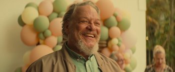 An older man with grey hair and a beard smiling for the camera