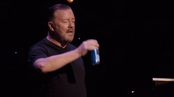 Movie still from “Ricky Gervais: SuperNature” (2022), directed by John L. Spencer – A man holding a can of beer in his hand; Medium shot, Over the shoulder angle