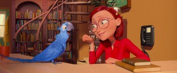 Movie still from “Rio” (2011), directed by Carlos Saldanha – A woman sitting at a table next to a blue bird; Medium shot, Over the shoulder angle