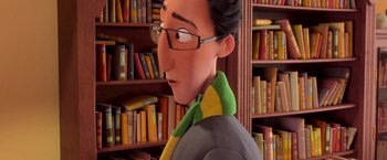 Movie still from “Rio” (2011), directed by Carlos Saldanha – A man with glasses and a tie in front of bookshelves; Close Up shot, High angle
