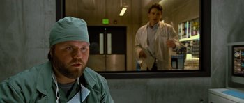 Movie still from “Rise of the Planet of the Apes” (2011), directed by Rupert Wyatt – A man in a green lab coat and a man in a white lab coat; Medium shot, Over the shoulder angle