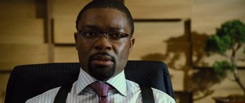 Movie still from “Rise of the Planet of the Apes” (2011), directed by Rupert Wyatt – A man in a suit and tie sitting in a chair; Close Up shot, Over the shoulder angle