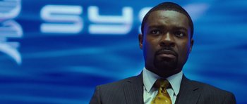 Movie still from “Rise of the Planet of the Apes” (2011), directed by Rupert Wyatt – A man wearing a suit and tie in front of a blue background; Close Up shot, Low angle