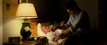 Movie still from “Rise of the Planet of the Apes” (2011), directed by Rupert Wyatt – An older man in a hospital bed being assisted by a younger man; Medium shot, Over the shoulder angle