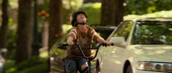 Movie still from “Rise of the Planet of the Apes” (2011), directed by Rupert Wyatt – A young boy riding a bike on the street; Medium shot, Over the shoulder angle