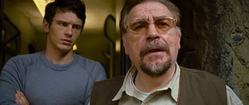 Movie still from “Rise of the Planet of the Apes” (2011), directed by Rupert Wyatt – A man with a beard and glasses is looking at the camera while a man with a goatee looks at the camera; Close Up shot, Over the shoulder angle