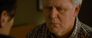 Movie still from “Rise of the Planet of the Apes” (2011), directed by Rupert Wyatt – An older man with a frowning look on his face; Close Up shot, Over the shoulder angle