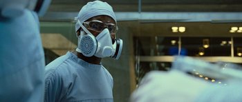 Movie still from “Rise of the Planet of the Apes” (2011), directed by Rupert Wyatt – A man wearing a surgical mask while standing in a room; Close Up shot, Over the shoulder angle