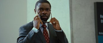 Movie still from “Rise of the Planet of the Apes” (2011), directed by Rupert Wyatt – A man in a suit and tie holding a pair of glasses; Close Up shot, Over the shoulder angle