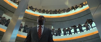 Movie still from “Rise of the Planet of the Apes” (2011), directed by Rupert Wyatt – A man in a gray suit and red tie looking up at the ceiling; Wide shot, Low angle