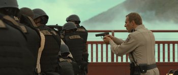 Movie still from “Rise of the Planet of the Apes” (2011), directed by Rupert Wyatt – A police officer holding a gun in front of a group of people; Medium shot, Over the shoulder angle