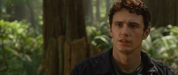 Movie still from “Rise of the Planet of the Apes” (2011), directed by Rupert Wyatt – A person in a forest with trees in the background; Close Up shot, Over the shoulder angle