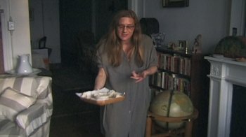 Movie still from “Roadrunner: A Film About Anthony Bourdain” (2021), directed by Morgan Neville – A woman holding a tray of food in a living room; Medium shot, High angle
