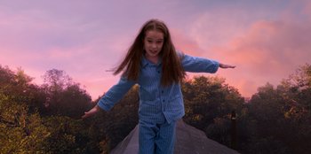 Movie still from “Roald Dahl's Matilda the Musical” (2022), directed by Matthew Warchus – A young girl in pajamas standing on top of a hill; Medium shot, Low angle