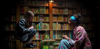 Movie still from “Roald Dahl's Matilda the Musical” (2022), directed by Matthew Warchus – Two people sitting in front of a book shelf; Medium shot, High angle
