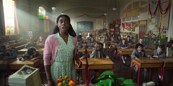 Movie still from “Roald Dahl's Matilda the Musical” (2022), directed by Matthew Warchus – A woman standing in front of a group of people; Medium shot, Over the shoulder angle