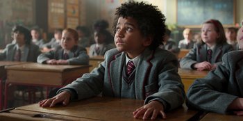 Movie still from “Roald Dahl's Matilda the Musical” (2022), directed by Matthew Warchus – A boy sitting at a table in a classroom; Close Up shot, High angle