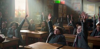 Movie still from “Roald Dahl's Matilda the Musical” (2022), directed by Matthew Warchus – A group of students raising their hands in a classroom; Wide shot, High angle