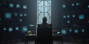 Movie still from “Roald Dahl's Matilda the Musical” (2022), directed by Matthew Warchus – A man sitting at a desk in front of a window; Wide shot, Low angle