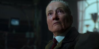 Movie still from “Roald Dahl's Matilda the Musical” (2022), directed by Matthew Warchus – An older man wearing a suit and tie looking off into the distance; Close Up shot, Low angle