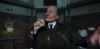 Movie still from “Roald Dahl's Matilda the Musical” (2022), directed by Matthew Warchus – An older man holding a cell phone up to his mouth; Close Up shot, Low angle