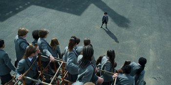 Movie still from “Roald Dahl's Matilda the Musical” (2022), directed by Matthew Warchus – A group of people watching a person stand in front of a crowd; Extreme Wide shot, High angle