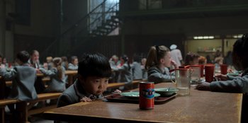 Movie still from “Roald Dahl's Matilda the Musical” (2022), directed by Matthew Warchus – A boy sitting at a table with a can of soda; Medium shot, High angle