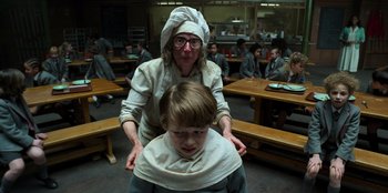 Movie still from “Roald Dahl's Matilda the Musical” (2022), directed by Matthew Warchus – An older woman and a young boy are in a kitchen; Medium shot, Low angle