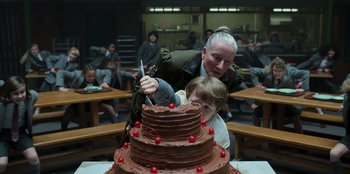 Movie still from “Roald Dahl's Matilda the Musical” (2022), directed by Matthew Warchus – A woman and a child cutting a chocolate cake; Medium shot, Over the shoulder angle