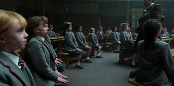 Movie still from “Roald Dahl's Matilda the Musical” (2022), directed by Matthew Warchus – A group of people sitting on benches in a room; Wide shot, High angle