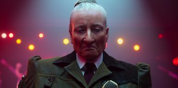 Movie still from “Roald Dahl's Matilda the Musical” (2022), directed by Matthew Warchus – An old man with a white beard wearing a jacket and tie; Close Up shot, Low angle