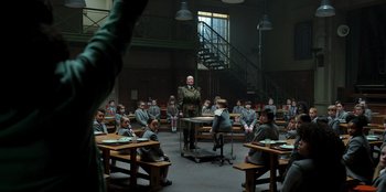 Movie still from “Roald Dahl's Matilda the Musical” (2022), directed by Matthew Warchus – A man in uniform standing in front of a group of people; Wide shot, High angle