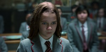 Movie still from “Roald Dahl's Matilda the Musical” (2022), directed by Matthew Warchus – A girl in a suit and tie looking at the camera; Close Up shot, Over the shoulder angle
