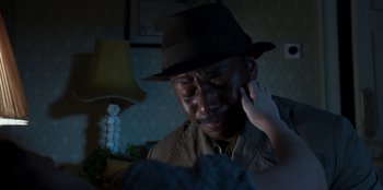 Movie still from “Roald Dahl's Matilda the Musical” (2022), directed by Matthew Warchus – A man in a hat is crying while holding his hand up to his ear; Close Up shot, High angle