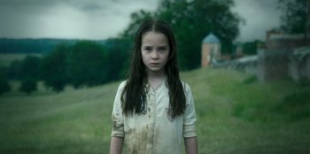 Movie still from “Roald Dahl's Matilda the Musical” (2022), directed by Matthew Warchus – A young girl with long hair standing in a grassy field; Medium shot, Low angle