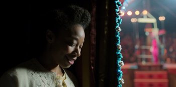Movie still from “Roald Dahl's Matilda the Musical” (2022), directed by Matthew Warchus – A young woman smiling while standing in front of a curtain; Close Up shot, Over the shoulder angle