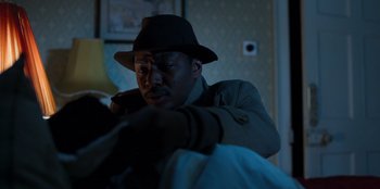 Movie still from “Roald Dahl's Matilda the Musical” (2022), directed by Matthew Warchus – A man wearing a hat looking down at a bag; Close Up shot, Over the shoulder angle