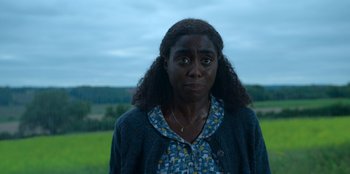 Movie still from “Roald Dahl's Matilda the Musical” (2022), directed by Matthew Warchus – A woman standing in front of a green field; Close Up shot, High angle