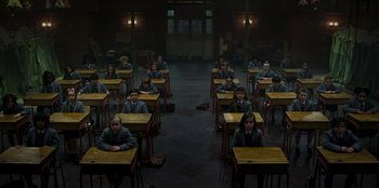 Movie still from “Roald Dahl's Matilda the Musical” (2022), directed by Matthew Warchus – A group of people sitting at desks in a room; Wide shot, High angle