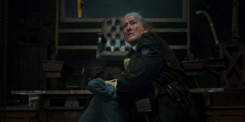 Movie still from “Roald Dahl's Matilda the Musical” (2022), directed by Matthew Warchus – An older man sitting in front of an old chair; Close Up shot, Over the shoulder angle